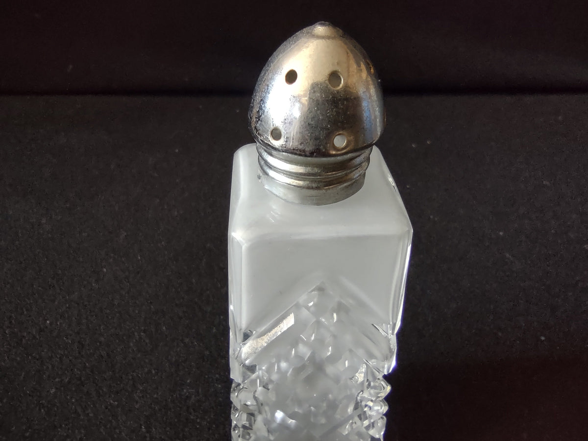 Close-up of vintage pressed glass salt shaker dome lid with tarnished silver-tone metal