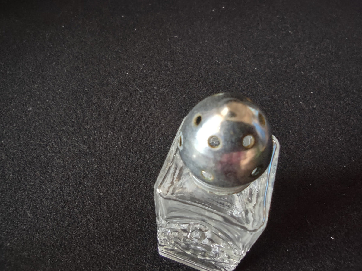 Detail of vintage pressed glass shaker showing stepped square base and diamond cut pattern
