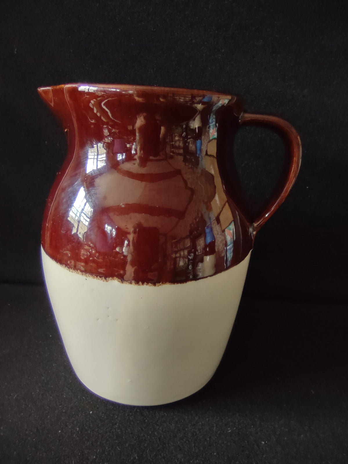 Vintage brown drip glaze stoneware pitcher, front view showing mahogany glaze over cream lower body