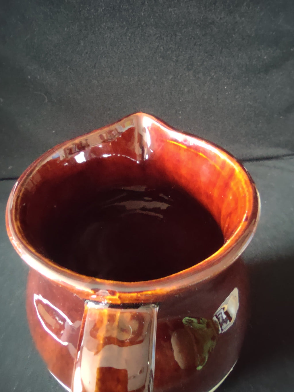 Top view of stoneware pitcher interior showing brown drip glaze