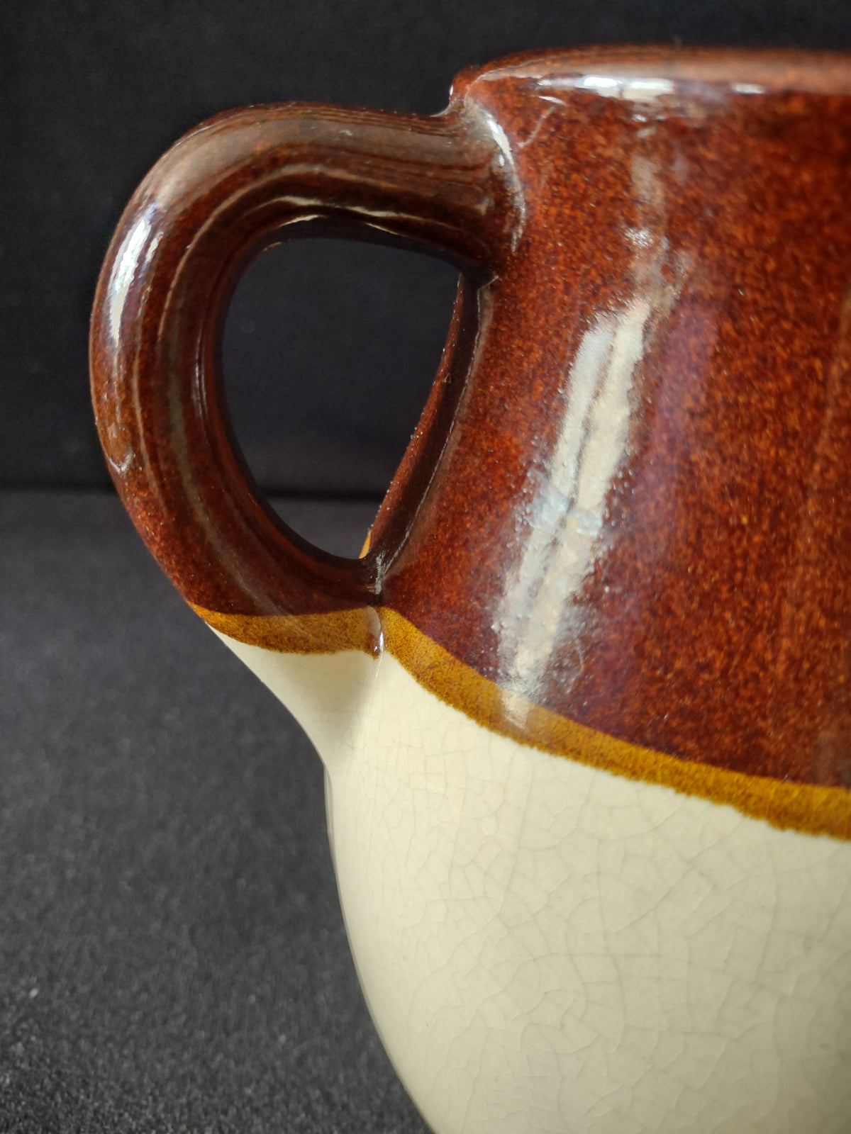 Angled top view of vintage stoneware pitcher showing pinched spout and brown glaze interior