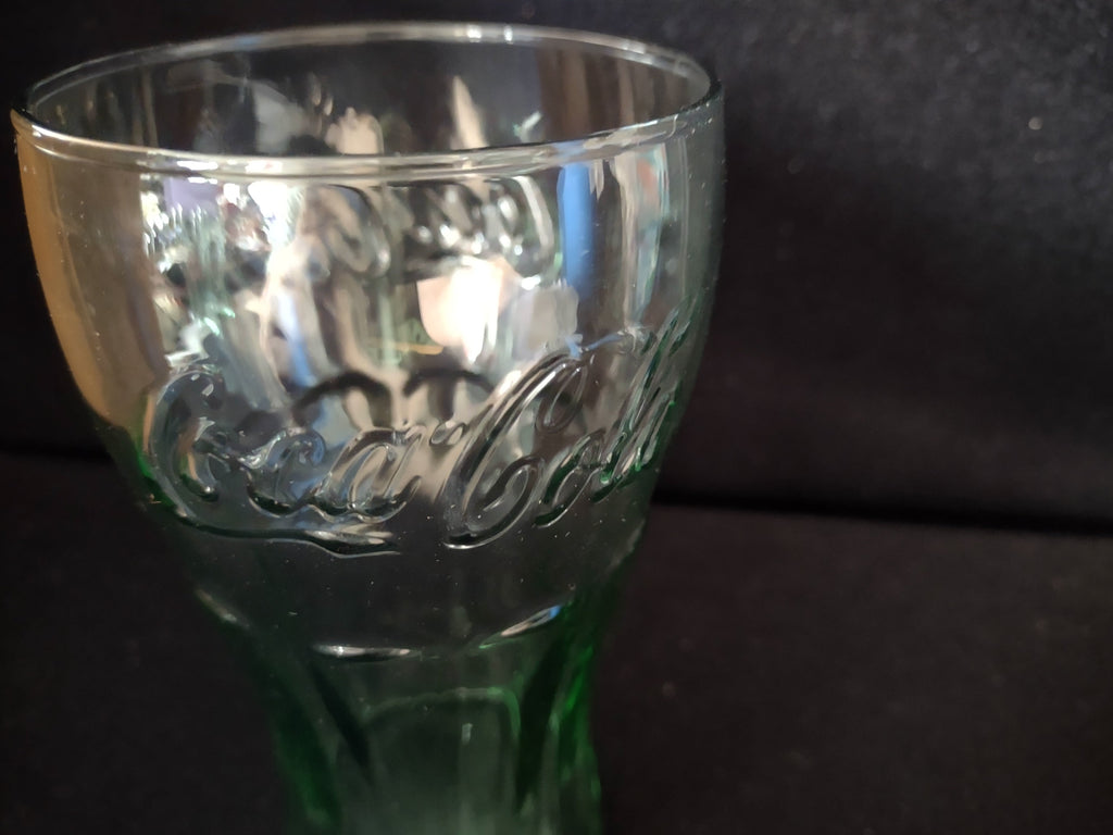 Close-up of Coca-Cola script on green glass tumbler, upper portion