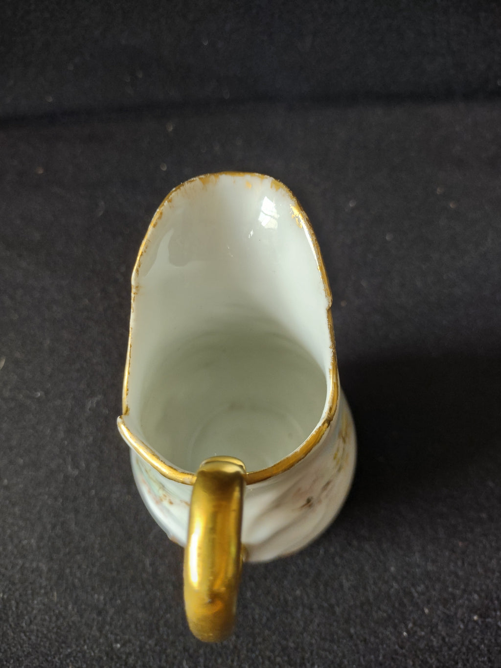 Miniature porcelain creamer - spout-on view showing swept spout form and gold rim