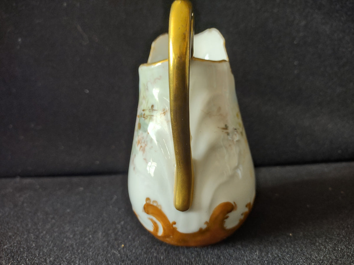 Miniature porcelain creamer - top down view into interior showing gold-rimmed spout opening