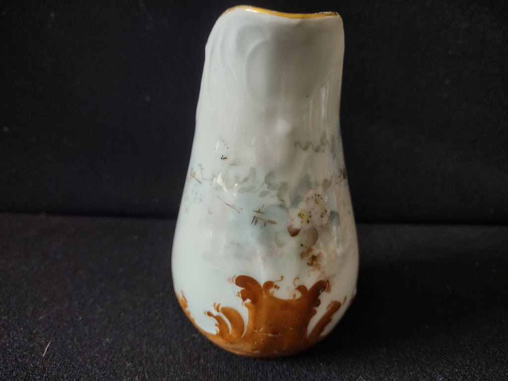 Miniature porcelain creamer - handle side view showing gold arched handle with wear and rubbing