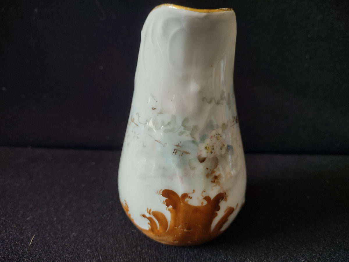 Miniature porcelain creamer - handle side view showing gold arched handle with wear and rubbing