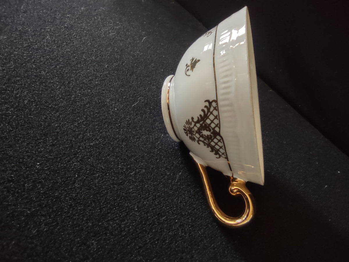 Schumann Bavaria cup side view showing black chinoiserie trellis lattice and gold fleur-de-lis pattern on white ground with scrolled gold handle