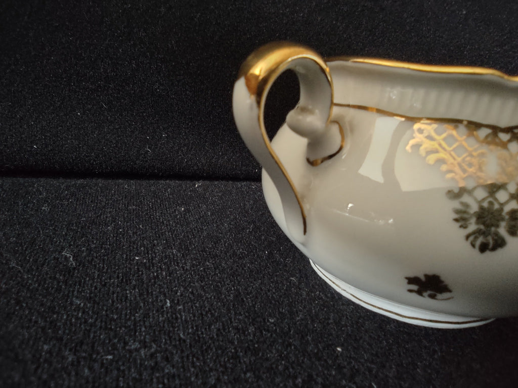 Seltmann Weiden Renate creamer close-up side view showing dark olive gold chinoiserie trellis lattice and central floral basket cartouche with peach rose accents