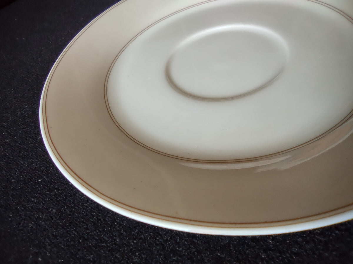 Hutschenreuther Chloe Huron Fontaine saucer angled close-up showing double platinum concentric lines at rim and cup ring well edge on warm off-white ground