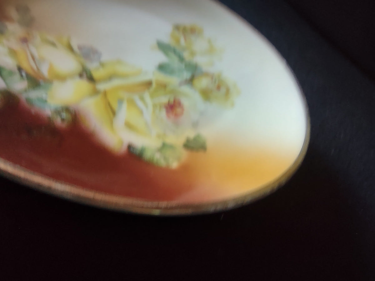 Hand-painted yellow roses plate angled view showing smooth unembossed rim profile and graduated mahogany to amber to off-white ground transition
