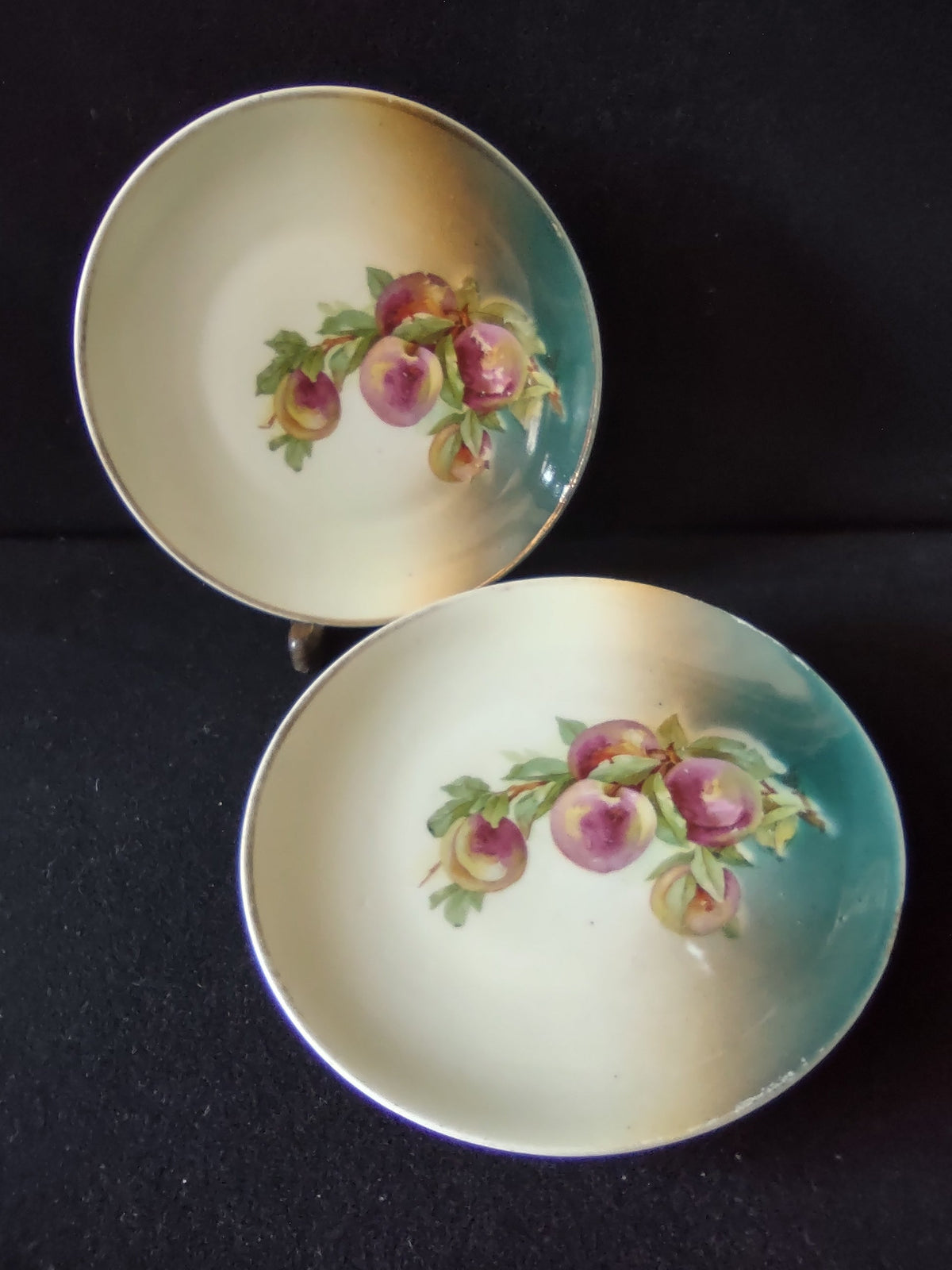 Vintage hand-painted German porcelain plate close-up of three ripe peaches in rose-purple and amber with green leaves on cream to teal graduated ground