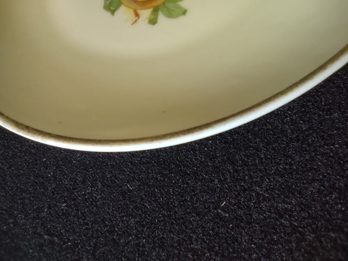 Hand-painted peaches plate rim close-up showing teal rim band wear and discoloration consistent with age on outer edge