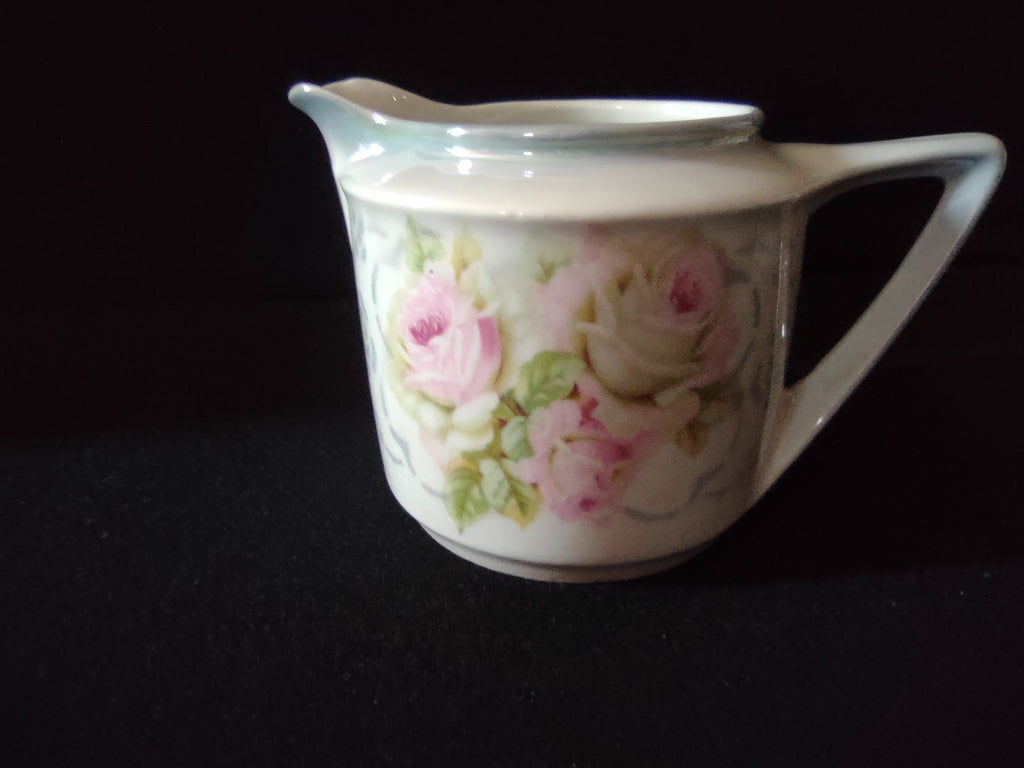 Vintage German porcelain pink roses cream pitcher showing large chip break on spout rim with substantial piece of pouring lip missing rough broken edges visible