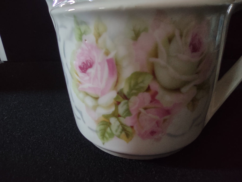 Pink roses porcelain creamer base view from above showing off-white unglazed foot rim with brown age spots and faded red circular backstamp with crossed symbol
