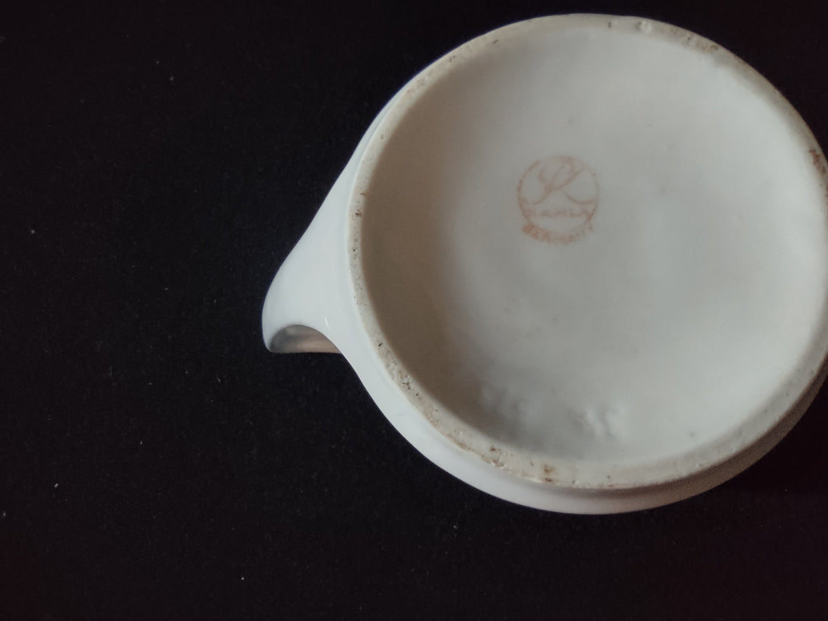 Pink roses porcelain creamer angled view showing loop handle side profile and soft pink rose decoration wrapping the squat cylindrical body