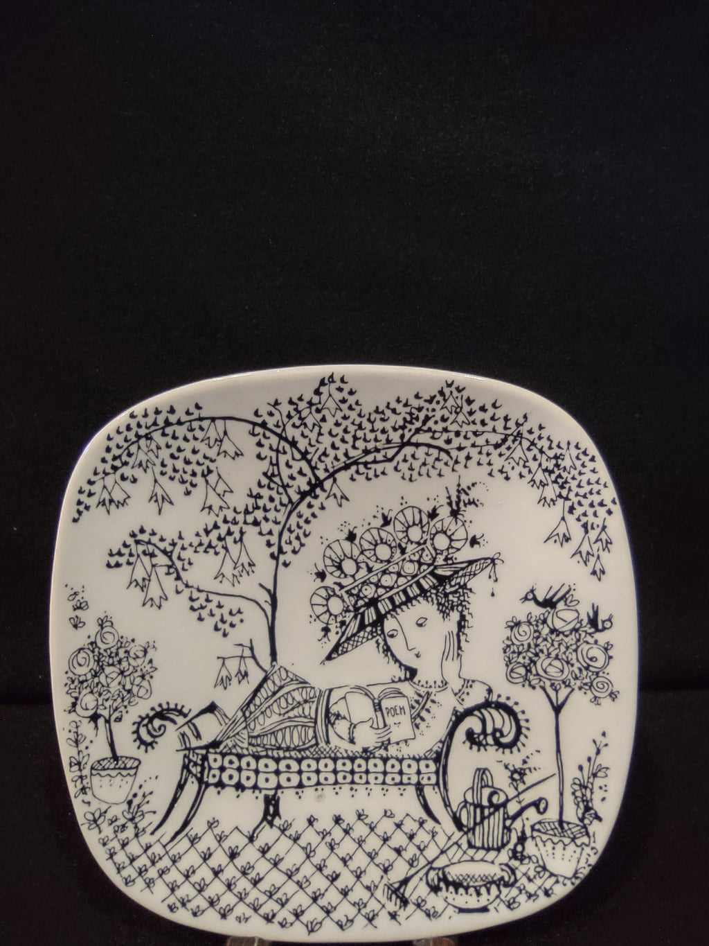 Vintage Rosenthal Studio-Linie Bjorn Wiinblad Fiesta square plate full front view showing complete black line garden scene with woman reading on chaise under flowering tree on white ground