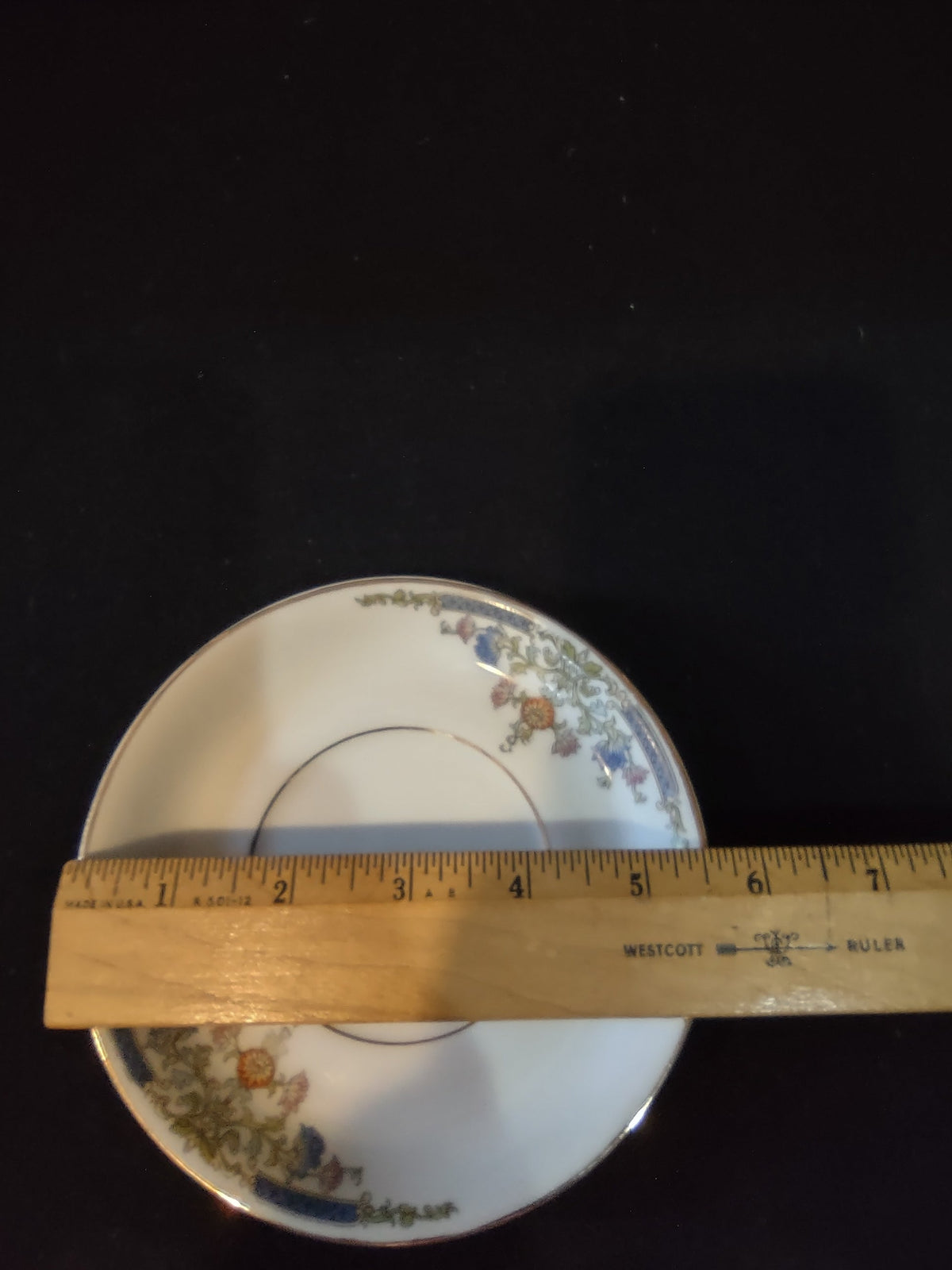Hutschenreuther Bavaria saucer close-up of top rim border showing central cartouche urn motif with blue bellflowers rust orange blooms and olive gold scrolling acanthus vine detail
