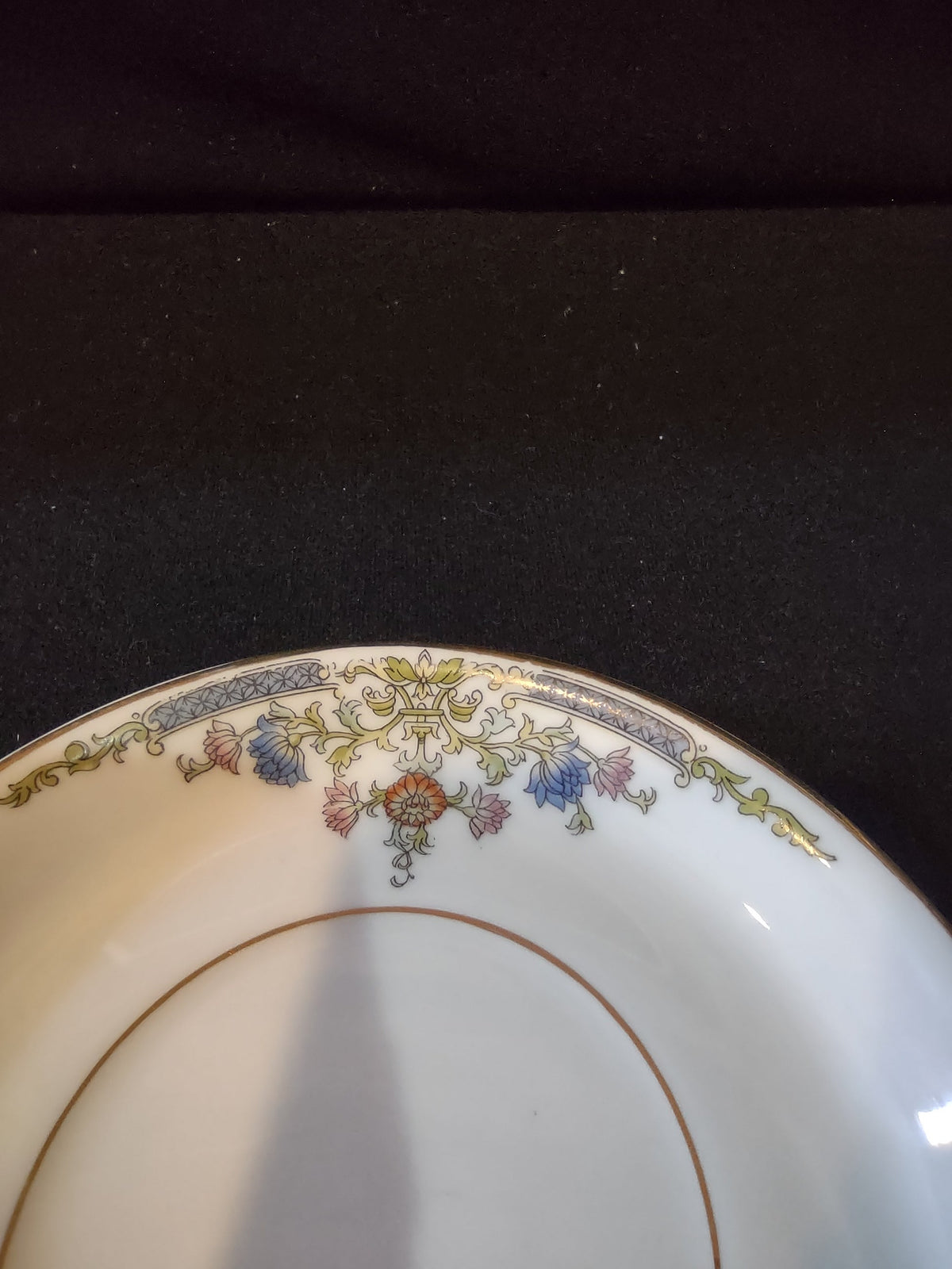 Hutschenreuther Bavaria saucer upper left quadrant close-up showing blue bellflower clusters rust orange chrysanthemum bloom gold acanthus scrollwork and deep blue ribbon band accent