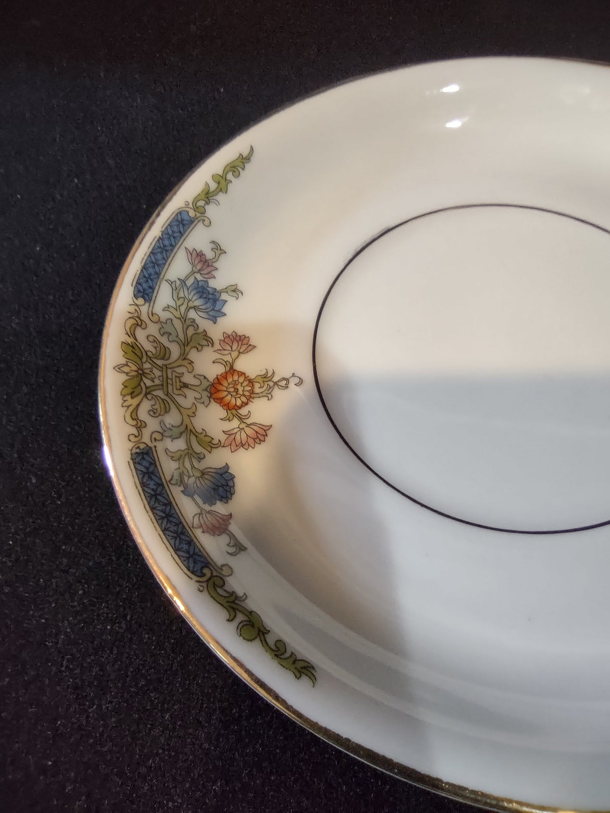 Hutschenreuther Bavaria saucer angled side profile view showing shallow well cup ring gold platinum rim line and floral border at lower left