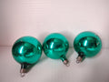 Three vintage teal green glass ball ornaments with ruler showing approximately 2.5 inch diameter