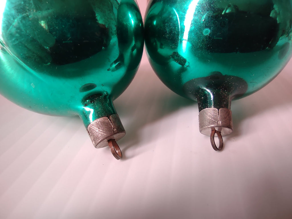 Close-up of teal green glass ornament showing paint loss and flaking on surface
