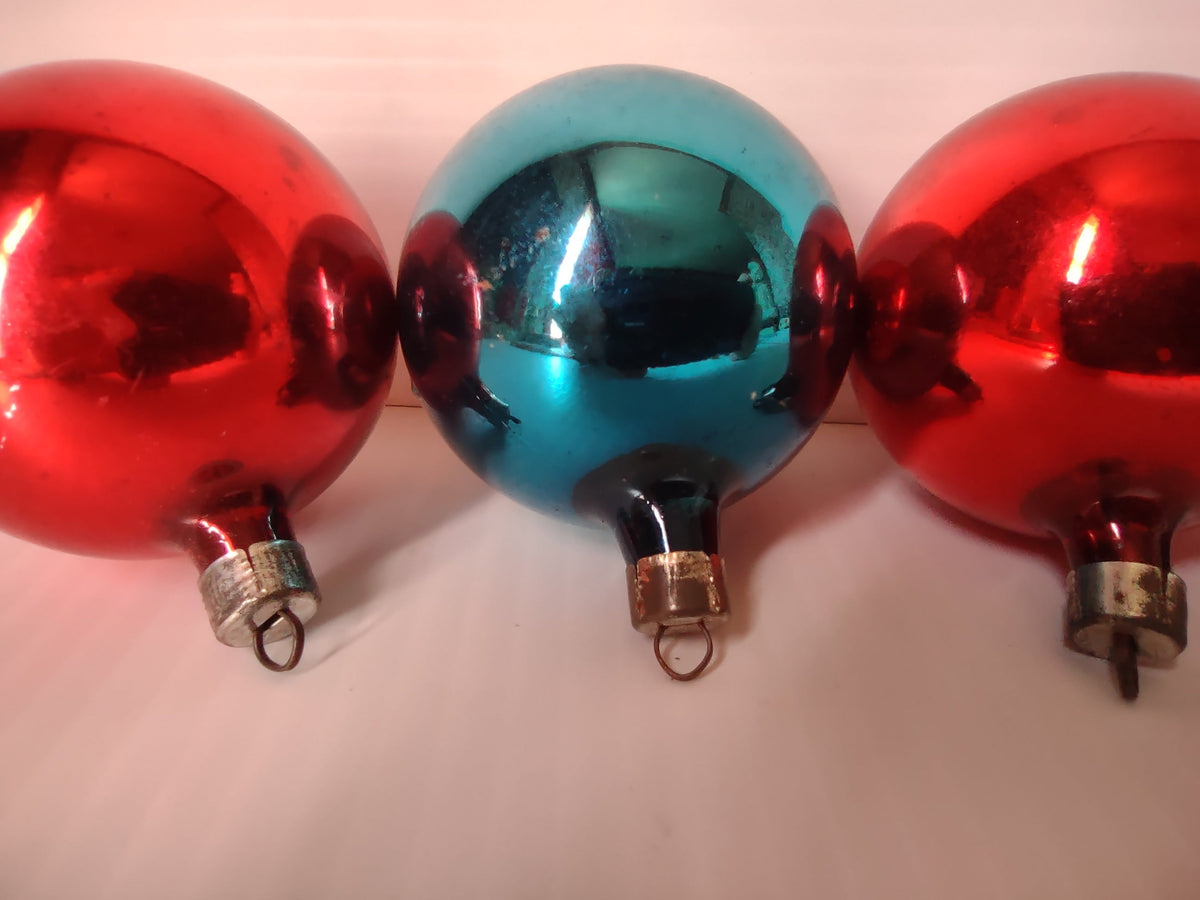 Set of 5 vintage glass ball ornaments — four red and one teal — lined up in a row