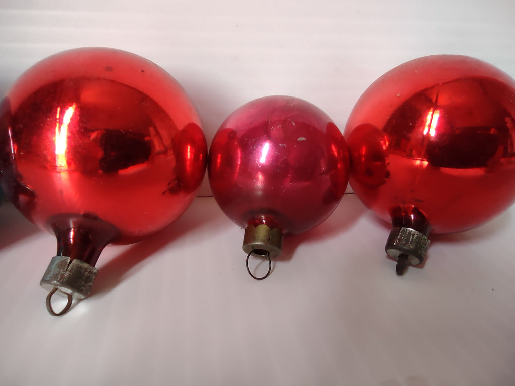 Set of 5 vintage glass ball ornaments showing tops — four red and one teal