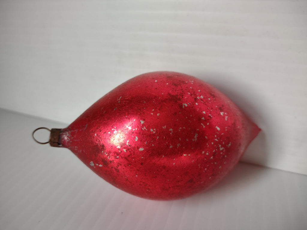 Vintage red teardrop glass ornament showing shiny reflective surface with extensive silvering flaking and wear