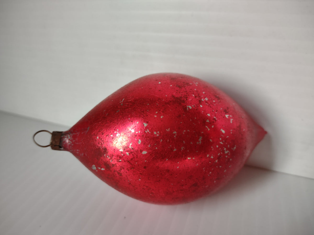 Vintage red teardrop glass ornament showing shiny reflective surface with extensive silvering flaking and wear