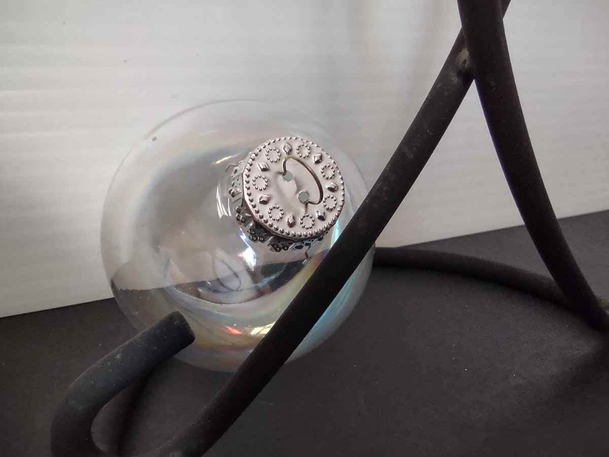 Close-up of ornate silver filigree dotted cap on vintage iridescent glass ball ornament