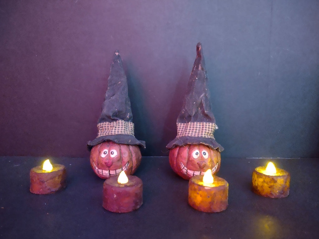 Two primitive folk art pumpkin witch hat figurines with 4 LED tealight candles shown with ruler