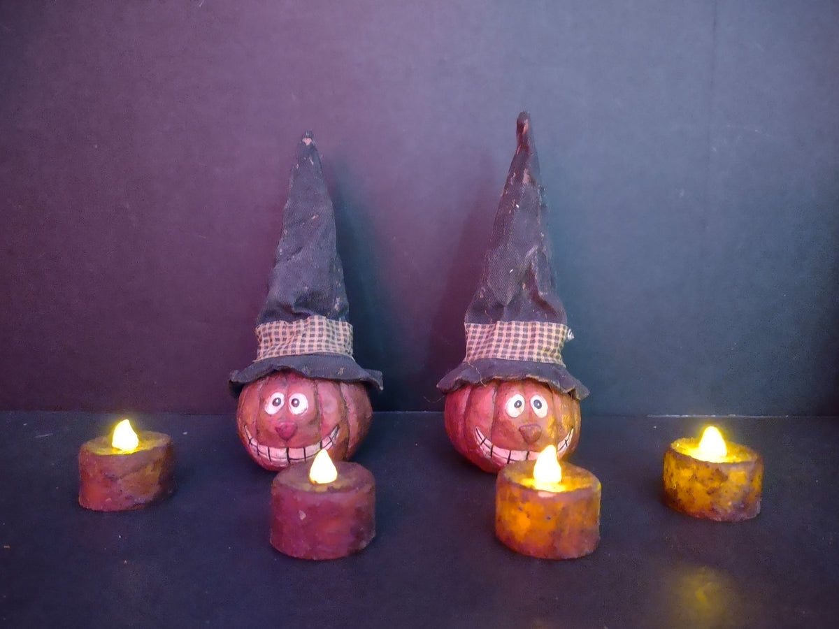 Two primitive folk art pumpkin witch hat figurines with 4 LED tealight candles shown with ruler