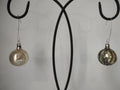Two vintage glass Christmas ornaments hanging on display stand — smooth off-white and glitter stripe ball