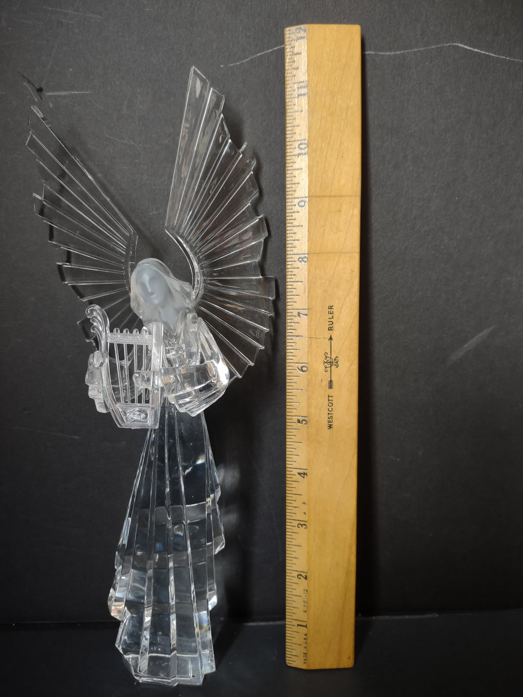 Vintage clear crystal acrylic angel figurine holding harp with large faceted wings, side view with ruler showing approximately 10 inch height