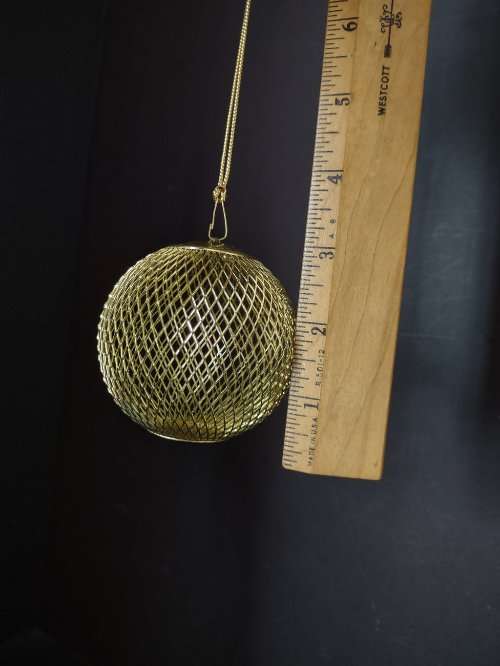 Vintage gold wire mesh ball ornament hanging on decorative branch