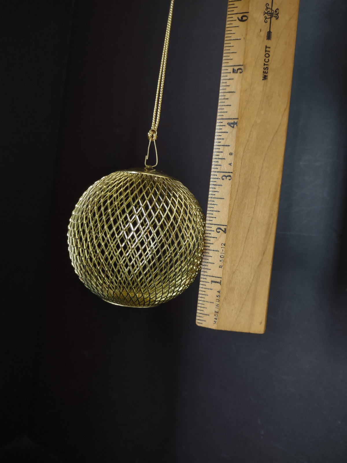 Vintage gold wire mesh ball ornament hanging on decorative branch