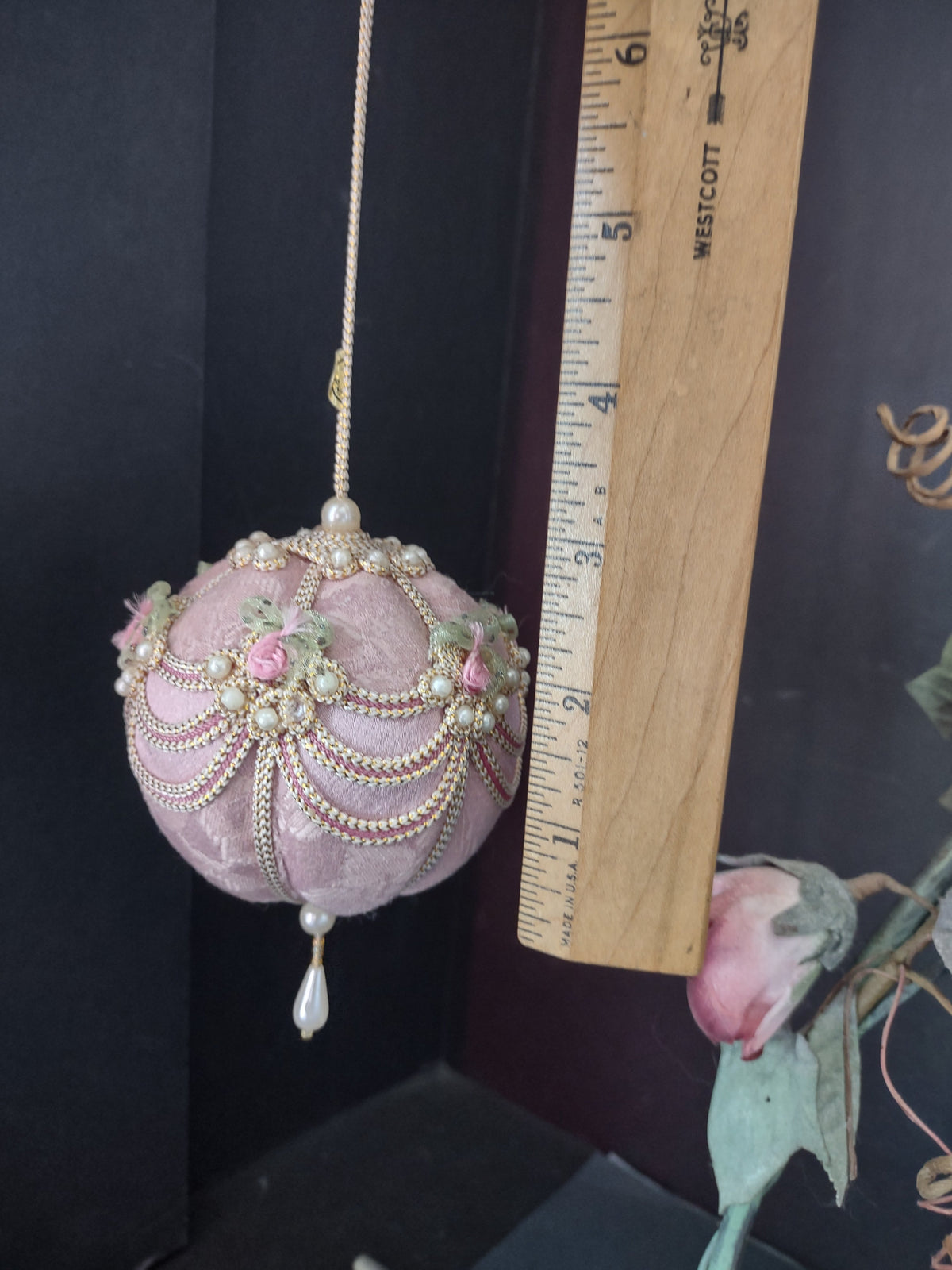 Vintage pink velvet ball ornament with pearl drop hanging on decorative stand full view