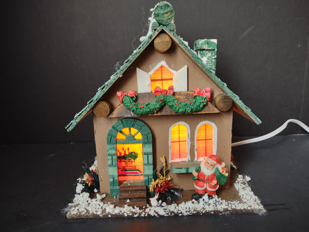 Vintage lighted wood Christmas village house front view with Santa figurine and glowing windows