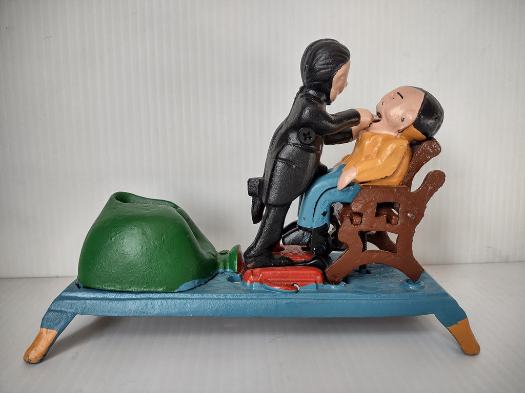 Vintage painted metal dentist mechanical coin bank with dentist and patient on blue platform