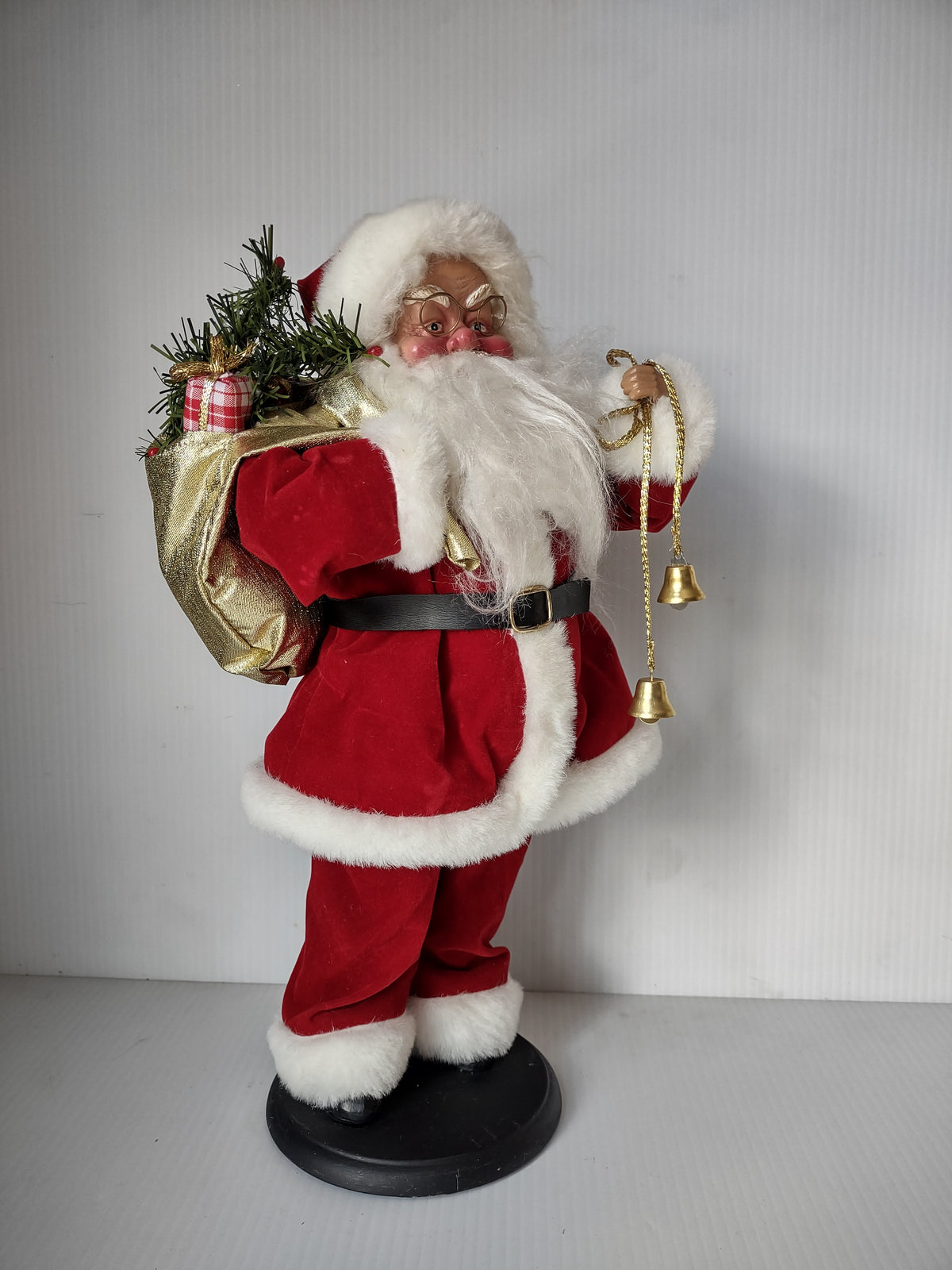 Santa Claus in red and white suit holding gold-tone bells and gift sack on black base