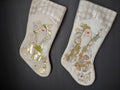 Pair of off-white Christmas stockings with gold and silver Santa teddy bear and house designs and diamond-pattern cuffs