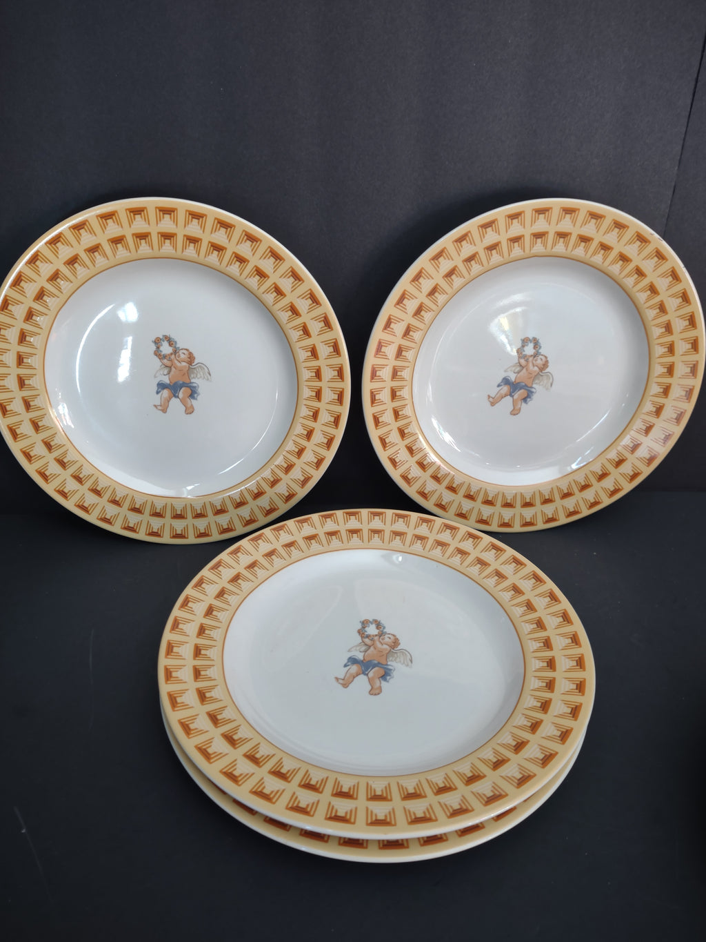 Four Fitz and Floyd Americana Cherub plate pieces with white centers and yellow borders