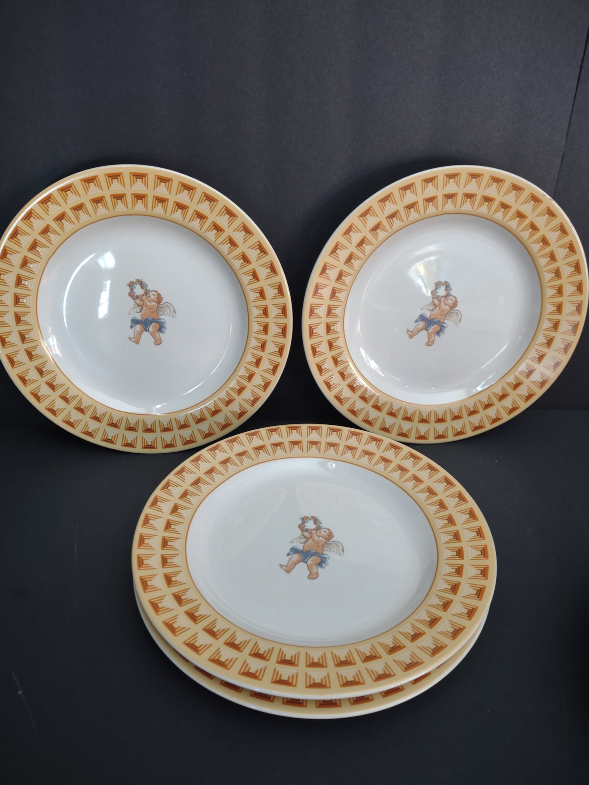 Four Fitz and Floyd Americana Cherub plate pieces with white centers and yellow borders