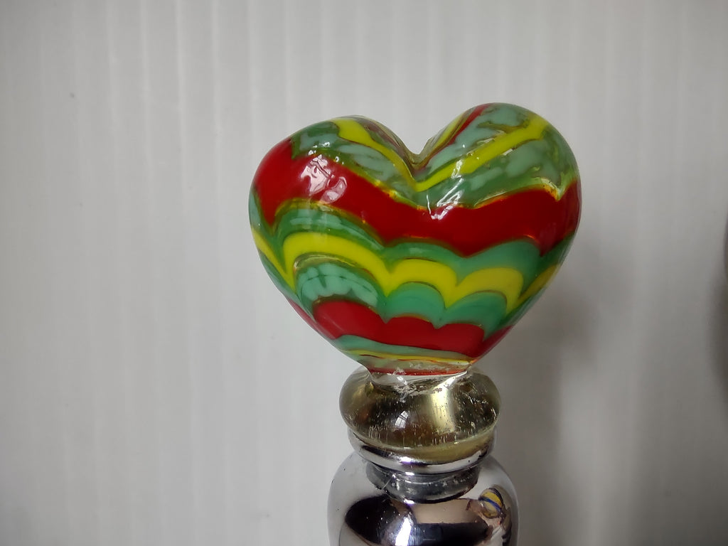 Close-up of red green yellow heart glass top and worn metal collar