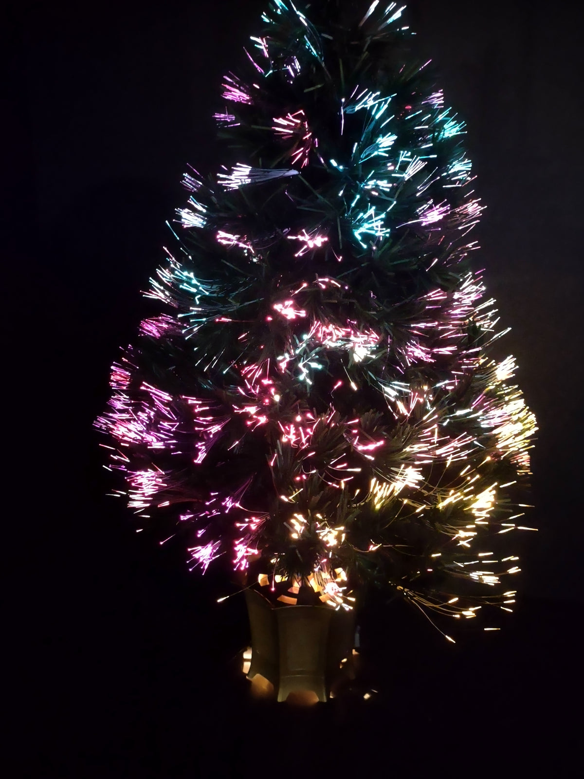 Vintage green fiber optic Christmas tree illuminated with pink blue white and gold lights in gold-tone base