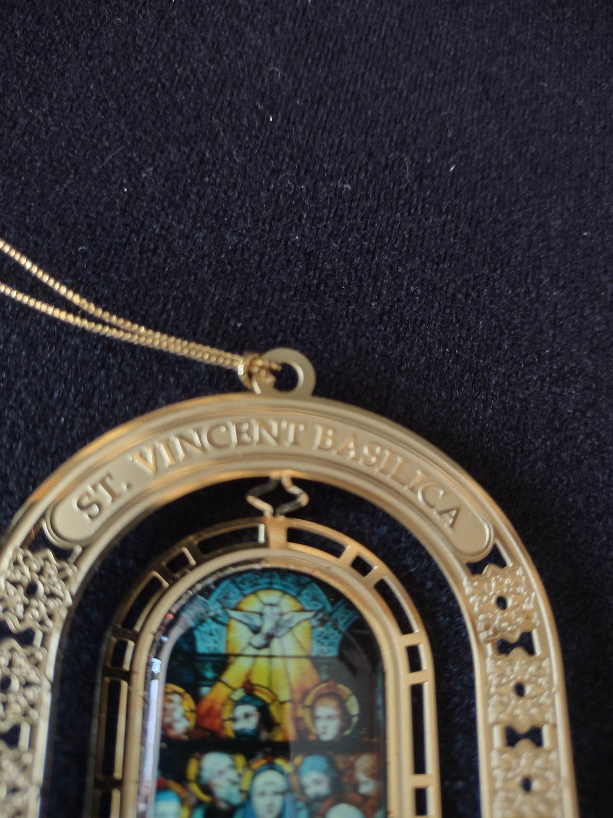 Gold-tone arched Pentecost ornament beside ruler