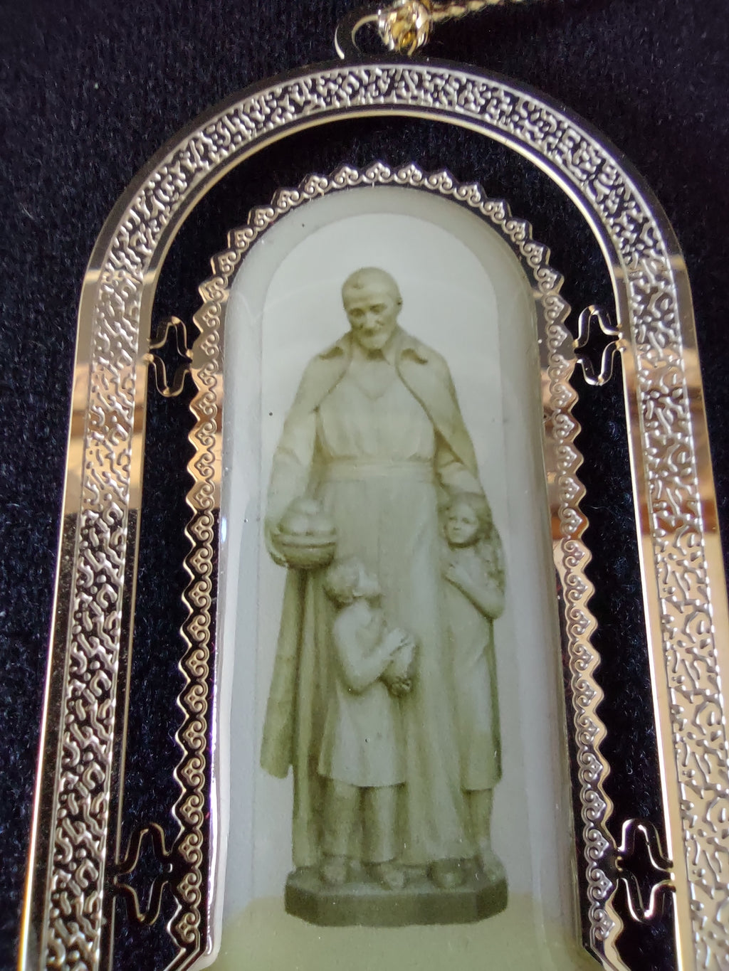 Close-up of the off-white Saint Vincent de Paul statuette inside the arched ornament frame