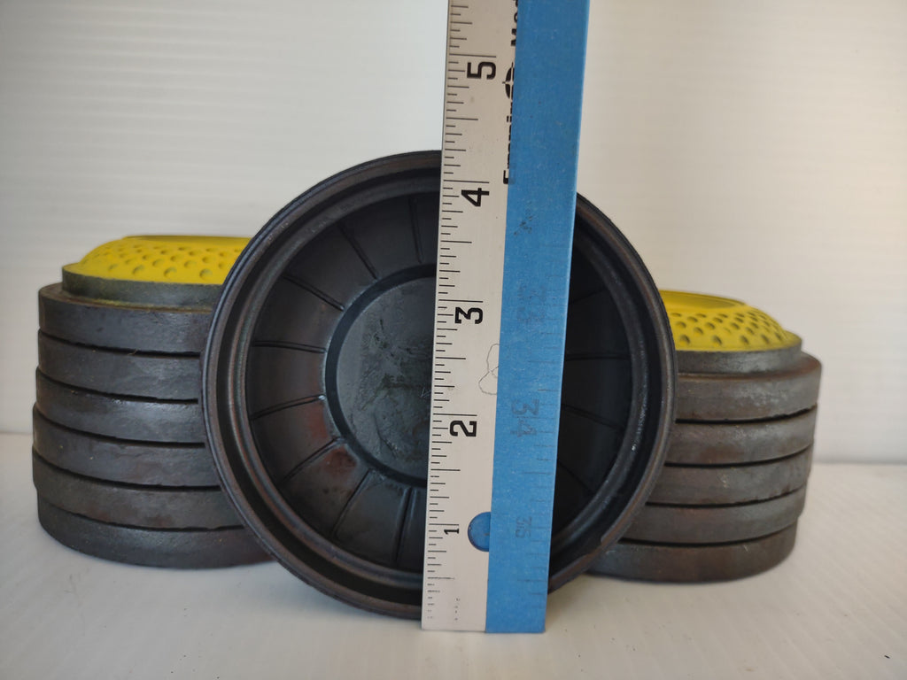 Underside of vintage clay target beside ruler and stacked targets