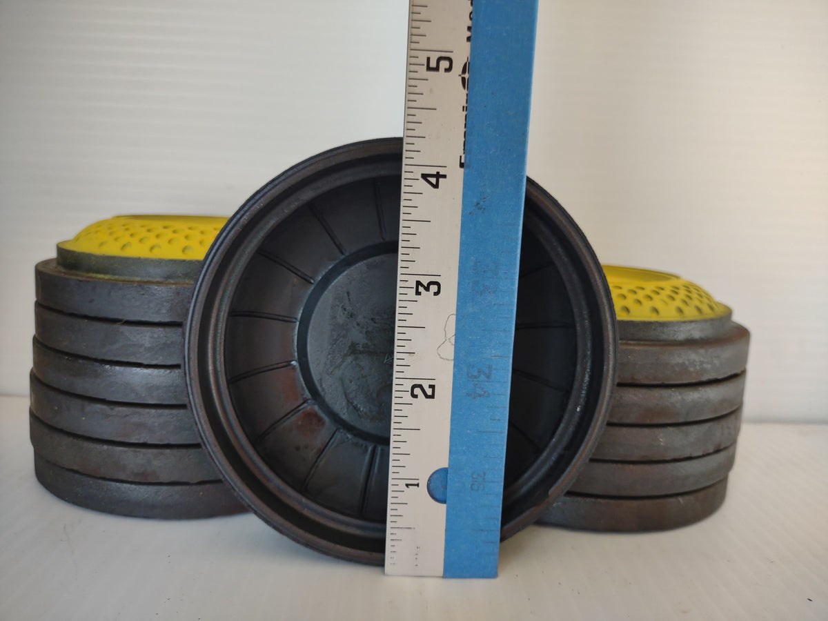 Underside of vintage clay target beside ruler and stacked targets