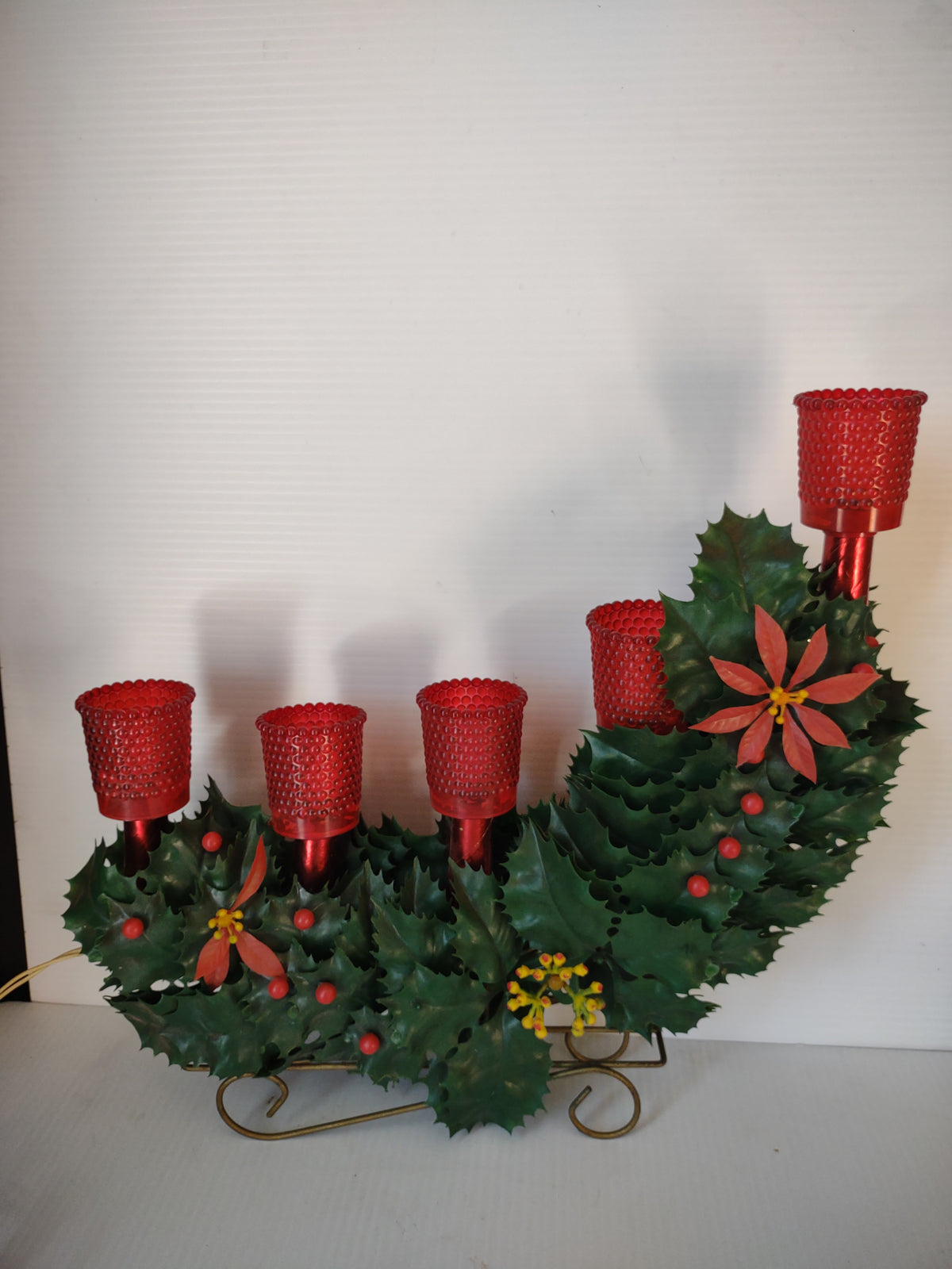 Vintage five-light Christmas candelabra illuminated with red shades and green holly
